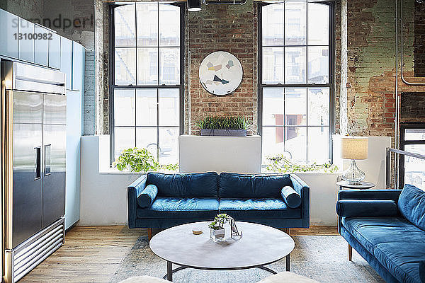 Blaue Sofas und Couchtisch vor den Fenstern im Kreativbüro an einem sonnigen Tag