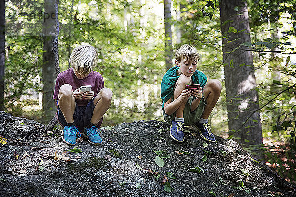 Jungen spielen im Wald Videospiele auf Smartphones