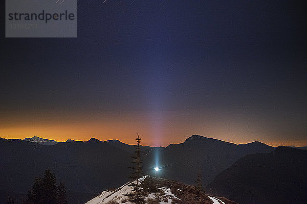 Blaues Licht auf dem Hügel vor der Silhouette der Bergkette bei Sonnenuntergang