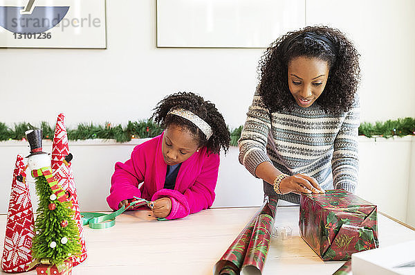 Mutter und Tochter packen zu Hause Weihnachtsgeschenke ein