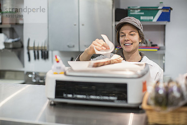 Lächelnder Arbeiter beim Zubereiten von Lebensmitteln während der Arbeit im Supermarkt