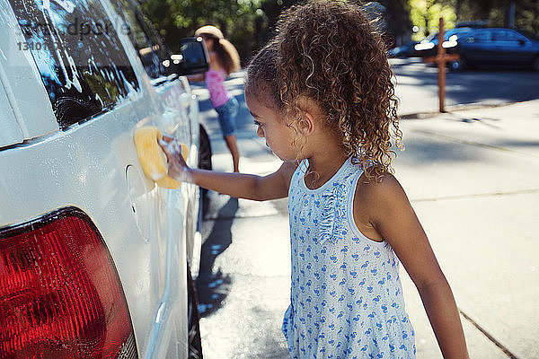 Mädchen waschen Auto in Einfahrt