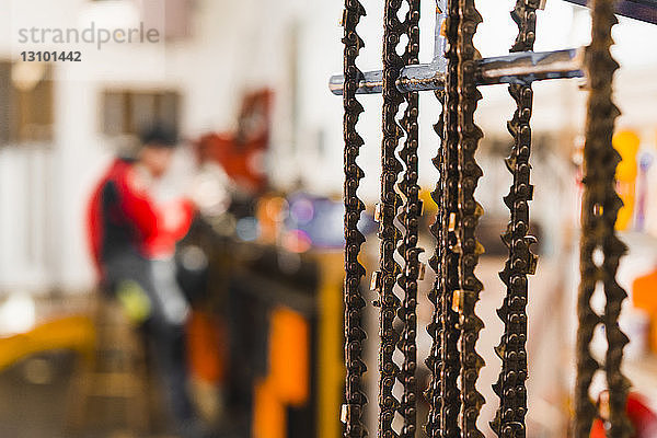 Nahaufnahme von Metallketten mit Mann im Hintergrund beim Workshop