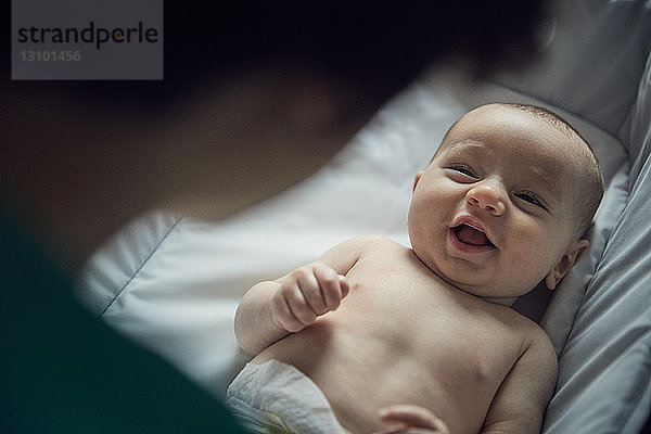 Ausgeschnittenes Bild einer Mutter  die ihren glücklichen Sohn zu Hause in der Krippe liegen sieht