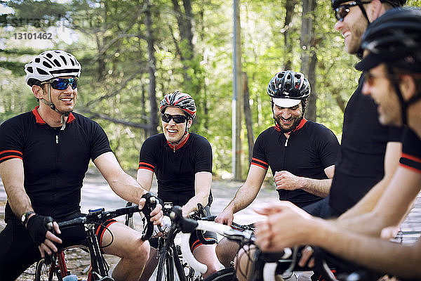 Glückliche männliche Radfahrer entspannen sich auf Fahrrädern