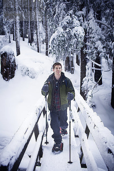 Junger Wanderer auf Steg im Winter