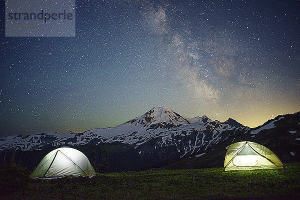 Beleuchtete Zelte auf dem Feld gegen Sternenhimmel