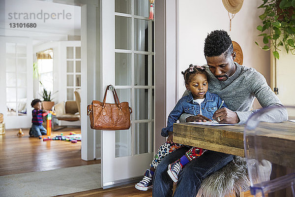 Tochter sieht Vater zu Hause beim Schreiben auf Papier