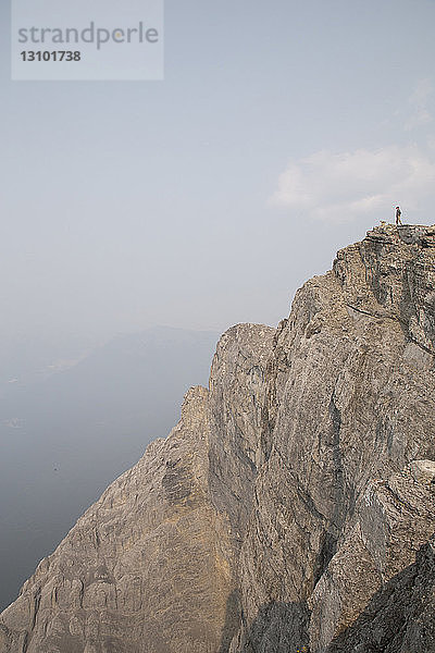 Fernansicht eines männlichen Wanderers  der auf einer Klippe gegen den Himmel steht