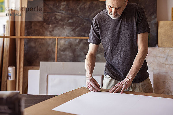 Männlicher Künstler beim Reiben auf Papier in der Werkstatt