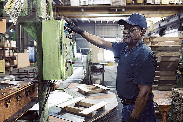 Seitenansicht eines Arbeiters  der eine Maschine bei der Arbeit in der Stahlindustrie benutzt