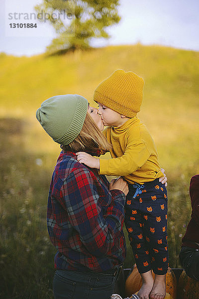 Ausgeschnittenes Bild eines Jungen von Mutter und Bruder  die sich auf dem Feld küssen