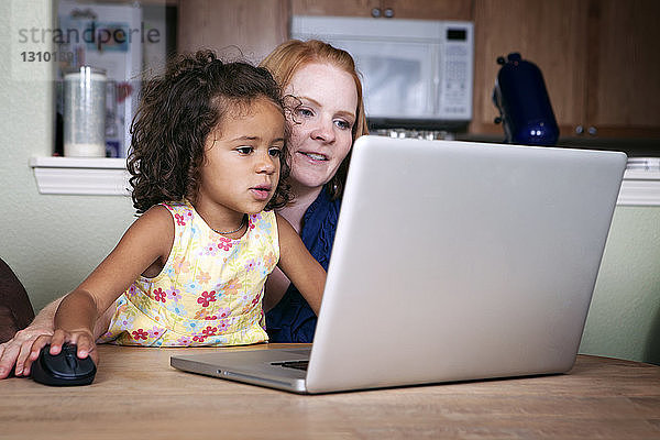 Mutter und Tochter mit Laptop am Tisch