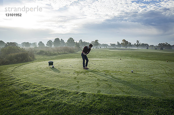 Mann spielt Golf auf dem Feld gegen den Himmel an einem sonnigen Tag