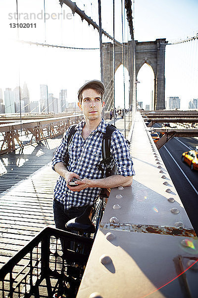 Nachdenklicher Mann steht am Geländer der Brooklyn Bridge