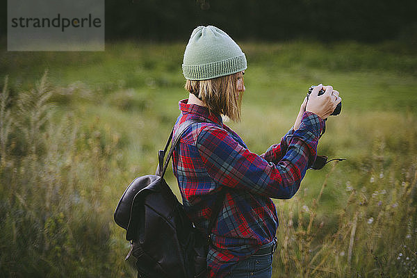 Seitenansicht einer Frau  die im Stehen auf einem Grasfeld fotografiert