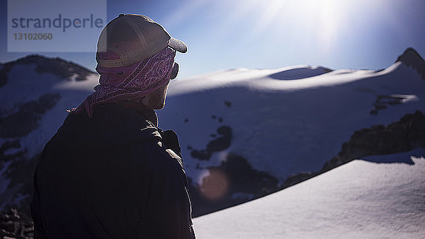 Mann steht an schneebedecktem Feld an einem sonnigen Tag