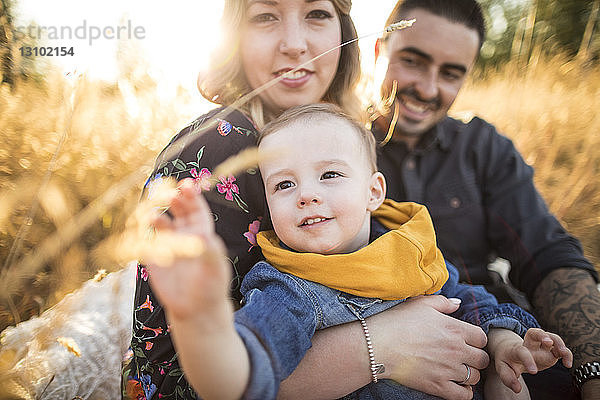 Glückliche Familie beim Picknick auf dem Feld bei Sonnenuntergang