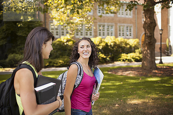Glückliche Frau sieht Freundin beim Spaziergang auf dem Campus an