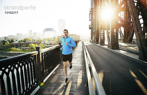 Mann rennt während einer Übung auf der Brücke gegen den klaren Himmel in der Stadt