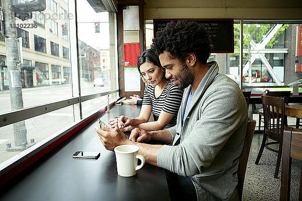 Multi-ethnisches Paar benutzt Tablet-Computer im Café