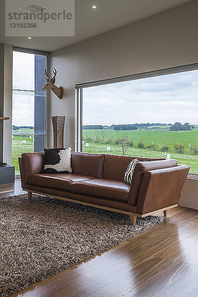 Couch auf Teppich gegen heimische Landschaft durch Fenster gesehen