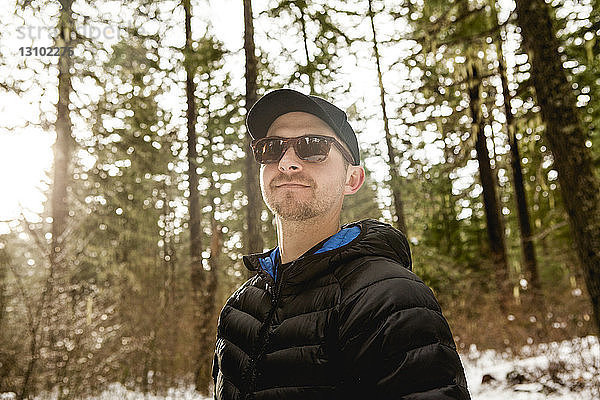 Tiefblick auf einen Mann mit Sonnenbrille  der im Winter im Wald wandert