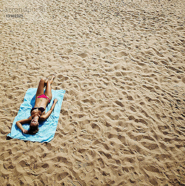 Hochwinkelansicht einer Frau beim Sonnenbaden am Strand
