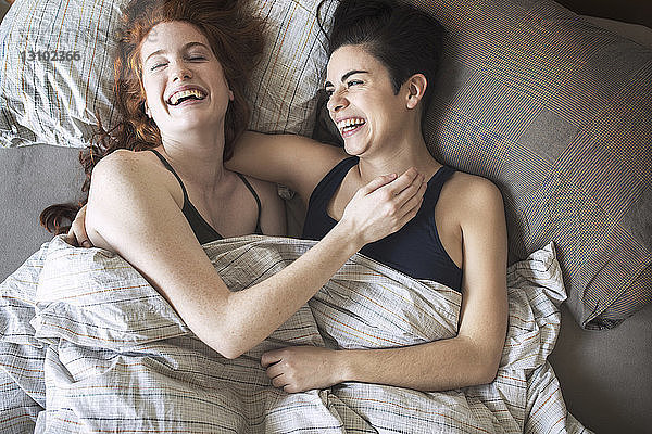 Hochwinkelansicht von fröhlichen Lesben  die sich auf dem Bett entspannen