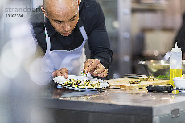 Chefkoch beim Garnieren von Speisen auf dem Teller in der Restaurantküche