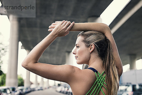 Rückansicht einer selbstbewussten Sportlerin  die ihre Arme unter der Brücke ausstreckt