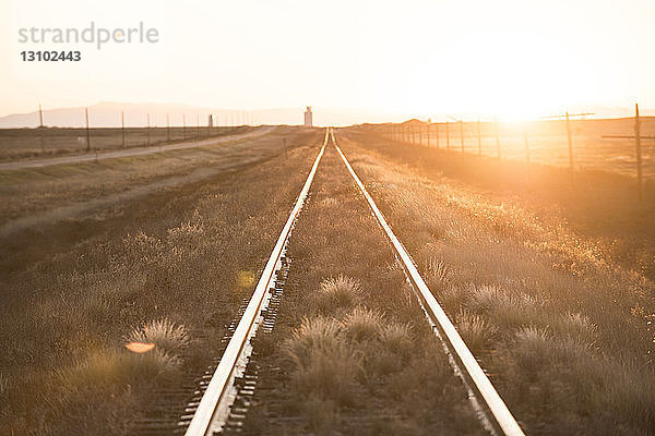 Ansicht der Eisenbahnschiene auf dem Feld gegen hellen Himmel bei Sonnenuntergang