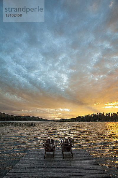 Hochwinkelansicht der Stühle auf dem Pier am See Lac Le Jeune im Paul Lake Provincial Park bei Sonnenuntergang