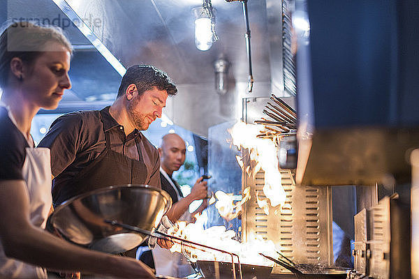 Köche bereiten Essen in der Restaurantküche in Flammen vor