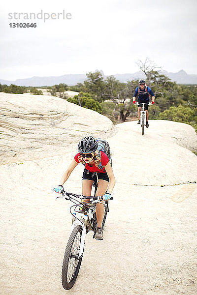 Fahrrad fahrende Paare auf Felsen vor klarem Himmel