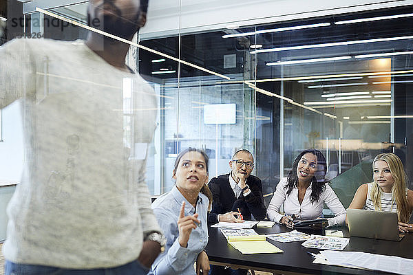 Multi-ethnische Kollegen betrachten Unternehmer bei einer Präsentation in einer Sitzung im Sitzungssaal