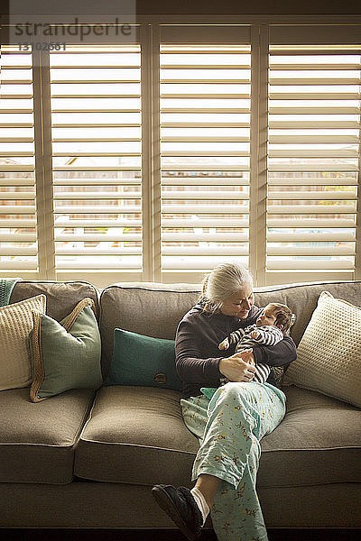 Großmutter spielt zu Hause mit dem Baby-Enkel auf dem Sofa
