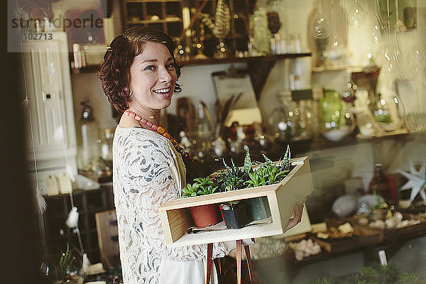Porträt eines glücklichen Kunden  der Pflanzen in einer Kiste im Gartenzentrum trägt