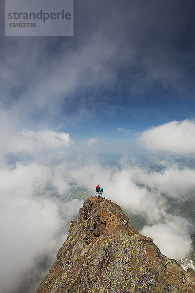 Hochwinkelaufnahme von Freunden  die auf dem Cheam Peak inmitten von Wolken stehen