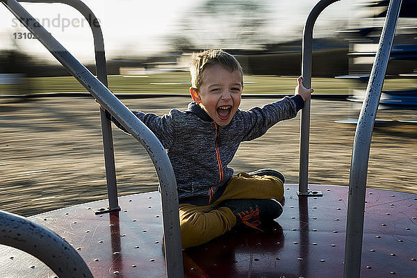 Porträt eines fröhlichen Jungen auf einem Karussell sitzend