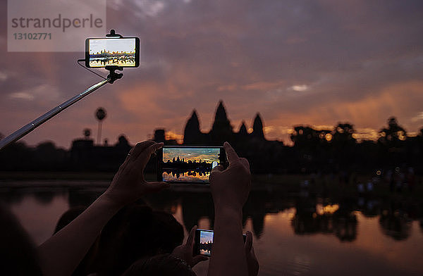 Ausschnitt von Touristen  die die Silhouette des Tempels Angkor Wat bei Sonnenuntergang fotografieren