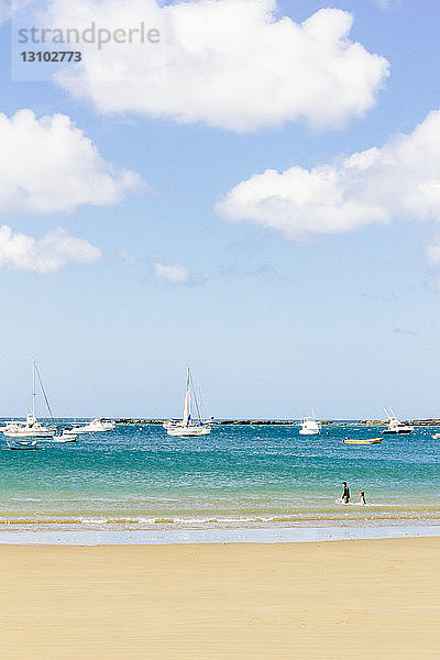 Szenische Ansicht des Strandes mit Segelbooten vor bewölktem Himmel