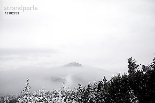 Idyllischer Blick auf Berge inmitten von Nebel gegen den Himmel im Winter