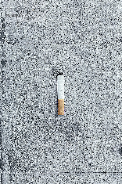 Draufsicht auf Zigarettenkippe auf der Straße