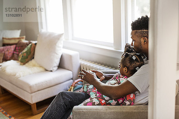 Seitenansicht eines Vaters am Tablet-Computer mit Kindern im Wohnzimmer