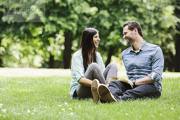 Glückliches Paar sieht sich an  während es sich auf einer Wiese im Park entspannt