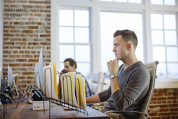 Männliche Kollegen arbeiten am Schreibtisch im Büro