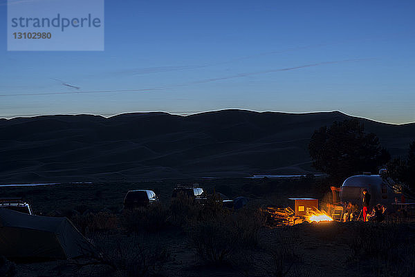 Freunde zelten in der Abenddämmerung im Great Sand Dunes National Park and Reserve gegen Berge und Himmel