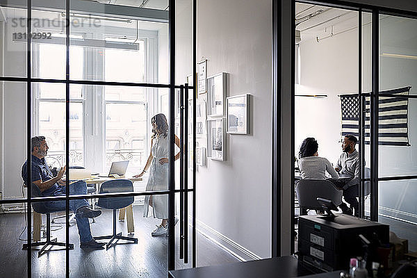 Unternehmer diskutieren in Vorstandsetagen in einem kreativen Büro mit Blick durch Fenster