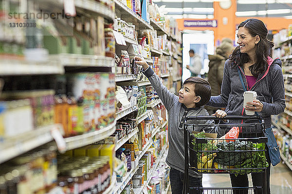 Junge kauft mit Mutter im Supermarkt ein